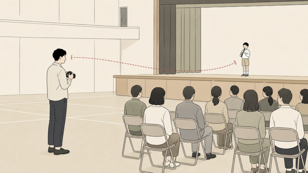 子どもの行事を見ながら必要な瞬間だけカメラを構える保護者